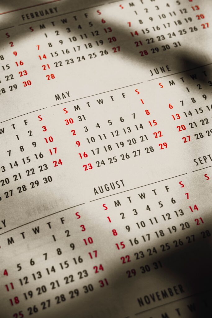 From above of shadows on paper calendar with month inscriptions and dates on sunny day